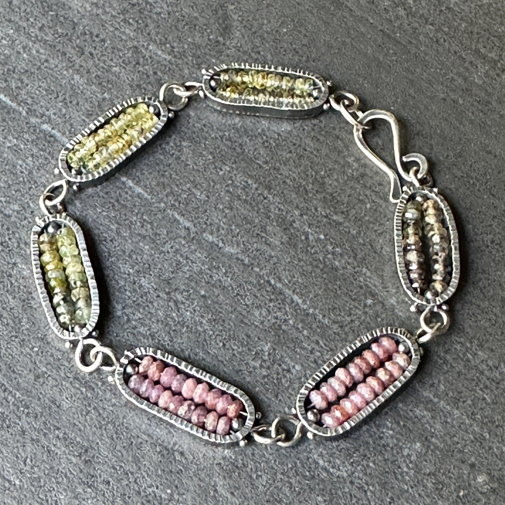 Bracelet with green and pink beads on a gray surface