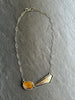 Necklace with asymmetrical pendant on a grey background